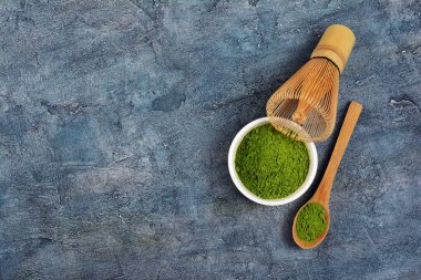 Organik yeşil matcha teapowder mavi beton zemin üzerine beyaz kase üzerinde üstten görünüm