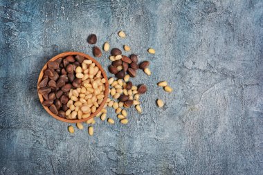 Sağlıklı ve lezzetli çam fıstığı kopya alanı mavi beton zemin üzerine küçük ahşap rustik kase üzerinde üstten görünüm