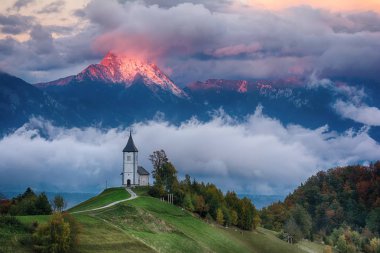 Kilise Jamnik Slovenya bulutlu gökyüzü ve dağlar arka plan mavi yeşil tepe üzerinde güzel gündoğumu peyzaj