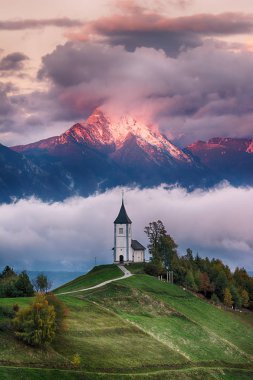 Kilise Jamnik Slovenya bulutlu gökyüzü ve dağlar arka plan mavi yeşil tepe üzerinde güzel gündoğumu peyzaj