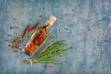 Aromatik veya aromalı zeytinyağı ile baharat ve otlar pul biber ve kekik kopya alanı mavi beton zemin üzerine cam şişede