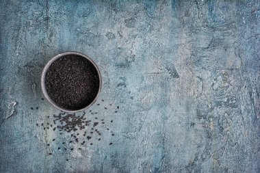 Organik doğal siyah susam kopya alanı mavi beton zemin üzerine kase üzerinde üstten görünüm