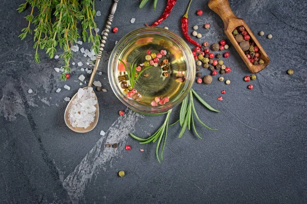 芳香或调味橄榄油在玻璃碗与香料和草药作为辣椒 迷迭香和百里香在黑色大理石背景与复制空间 — 图库照片