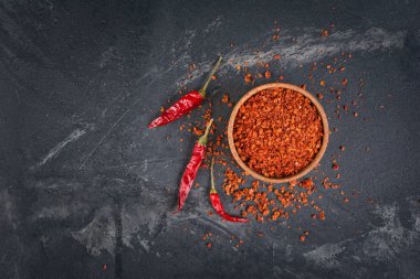 Ezilmiş kuru kırmızı sıcak biber biber ahşap kase üstten görünüm kopya alanı siyah mermer zemin üzerine