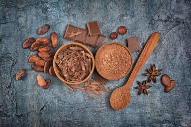 Çikolata parçaları, bar ve kakao tozu mavi beton zemin üzerine şekerlemeler için baharat ile üstten görünüm