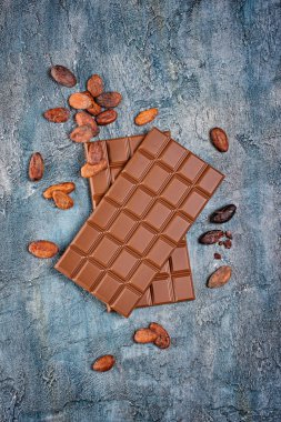 İki lezzetli koyu çikolata kakao çekirdekleri ile üstten görünüm mavi beton zemin üzerine