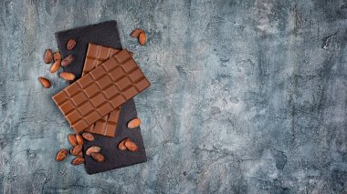 İki lezzetli koyu çikolata kakao çekirdekleri ile üstten görünüm siyah arduvaz kurulu ve mavi beton arka plan kopya alanı ile