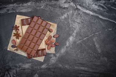 Baharatlı koyu çikolata kakao çekirdekleri ve anason yıldız ile üstten görünüm parşömen kağıt ve siyah mermer arka plan kopya alanı ile