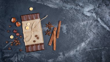 Koyu çikolata kahve çekirdekleri, bütün fındık içi ve tarçın ve anason yıldız olarak baharatlar ile üstten görünüm kopya alanı siyah mermer zemin üzerine