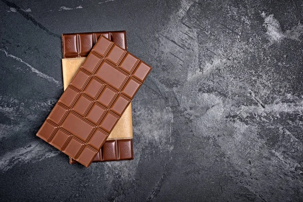 Bovenaanzicht Van Twee Lekkere Donkere Chocolade Repen Kraftpapier Zwart Marmeren — Stockfoto