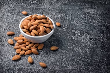 Kopya alanı koyu gri beton zemin üzerine beyaz kase sağlıklı tüm badem