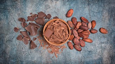 Mavi beton zemin üzerine koyu çikolata parçaları ve kakao çekirdekleri ile fiş üstten görünüm