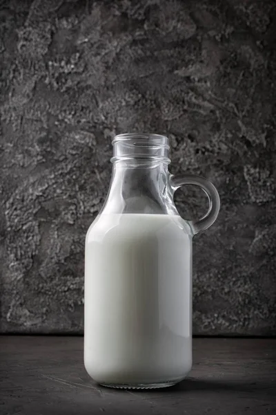 Healthy natural cow milk in glass bottle on dark gray concrete background