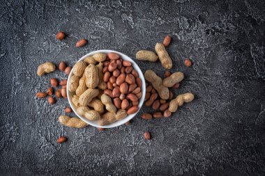 Koyu gri beton zemin üzerine beyaz kase doğal tüm fıstık üstten görünüm