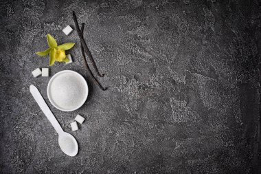 Kopya alanı gri beton zemin üzerine beyaz toz ve küp şeker vanilya çubukları ve çiçek ile üstten görünüm