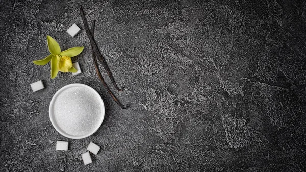 白色砂糖和立方体糖的顶视图与香草棍子和花在灰色混凝土背景与拷贝空间 — 图库照片