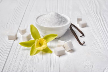 Beyaz toz ve şeker vanilya sarı çiçek ile küpleri ve hafif ahşap arka plan üzerinde sopa