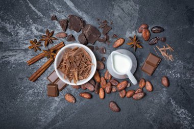 Çikolata Beyaz kase, süt ve baharatlar ile bütün kakao çekirdekleri üstten görünüm kopya alanı siyah mermer zemin üzerine şekerlemeler için madde olarak