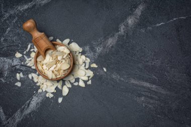 Ahşap kase kopya alanı siyah mermer zemin üzerine şekerlemeler için madde olarak badem dilimleri üstten görünüm