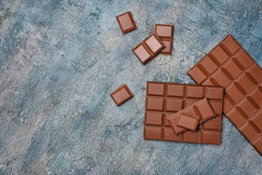Lezzetli kırık çikolata atıştırma veya kopya alanı mavi beton zemin üzerine şekerlemeler için madde olarak üstten görünüm