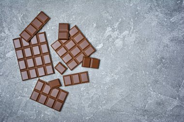 Lezzetli kırık çikolata atıştırma veya kopya alanı gri beton zemin üzerine şekerlemeler için madde olarak üstten görünüm