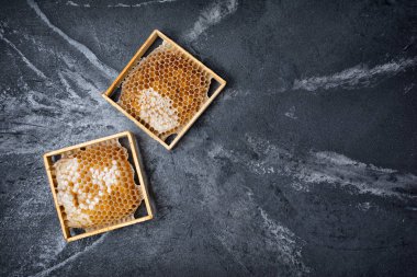 Kopya alanı siyah mermer zemin üzerine sağlıklı beslenmesi için organik madde olarak ahşap çerçeveler içinde doğal ürün petek üzerinde üstten görünüm