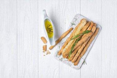 Geleneksel İtalyan meze grisini biberiye baharat ve zeytinyağında sauceboat üstten görünüm kopya alanı beyaz ahşap zemin üzerine