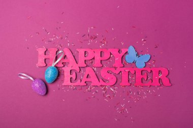 Mutlu Paskalya ve parlak renkli şeker şeker veya dekor mor zemin üzerine kabartma olarak konfeti ile ışıltılı yumurta pembe metin üstten görünüm