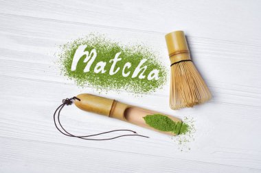 Organik yeşil matcha çay tozu bambu chasen ve beyaz ahşap zemin üzerinde kepçe ile gelen yazı üzerine üstten görünüm