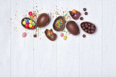 Üstten görünüm parlak renkli badem ve şeker şeker veya kopya spac Beyaz ahşap zemin üzerine konfeti ile çikolata geleneksel Paskalya yumurta üzerinde