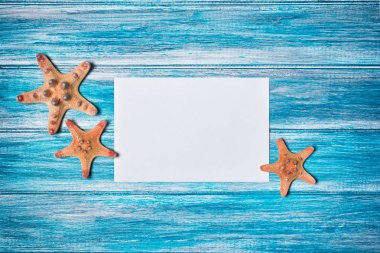 Mavi ahşap zemin üzerine deniz yıldızı ile mockup fotoğraf ya da yazı için beyaz kağıt kartı üzerinde Üstten Görünüm