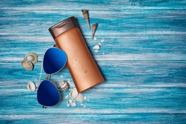 Güneş kremi ve güneş gözlüğü ile bronz şişe mavi ahşap arka plan kopya alanı ile zamanında tatil kavramı olarak üzerinde Üstten Görünüm