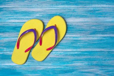 Mavi ahşap arka plan kopya alanı ile zamanında tatil kavramı olarak parlak sarı flip flop üzerinde Üstten Görünüm