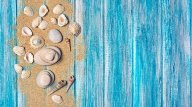 Deniz kabuklarını kumla üstten görünüm olarak kopya alanı ile tatil zaman kavramı mavi ahşap arka plan üzerinde