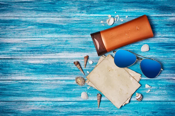 Vintage fotoğraf kartı mock-up şişe güneş kremi, güneş gözlüğü ve kopya alanı mavi ahşap zemin üzerine kabukları ile üzerinde Üstten Görünüm