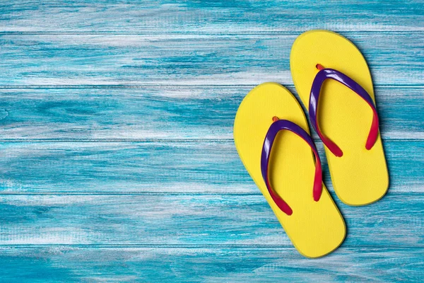 Mavi ahşap arka plan kopya alanı ile zamanında tatil kavramı olarak parlak sarı flip flop üzerinde Üstten Görünüm