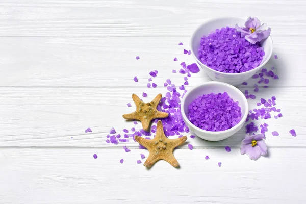 Flavored purple sea salt crystals with violet flower and starfishes on white