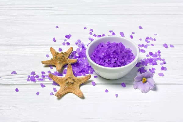 Cristaux de sel de mer violet aromatisés avec fleur violette et étoiles de mer sur blanc — Photo