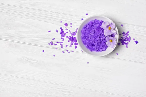 Ароматизовані фіолетові морські кристали солі для ванни з фіолетовою квіткою на білому — стокове фото