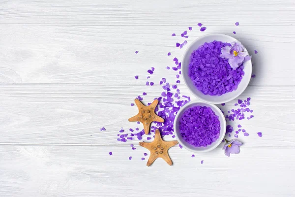 Smaksatt lila havssalt kristaller med violett blomma och starfishes på vit — Stockfoto