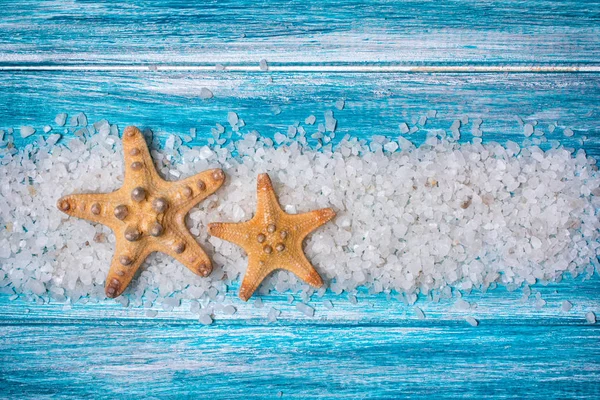 Sea salt crystals and starfishes on blue background — Stock Photo, Image