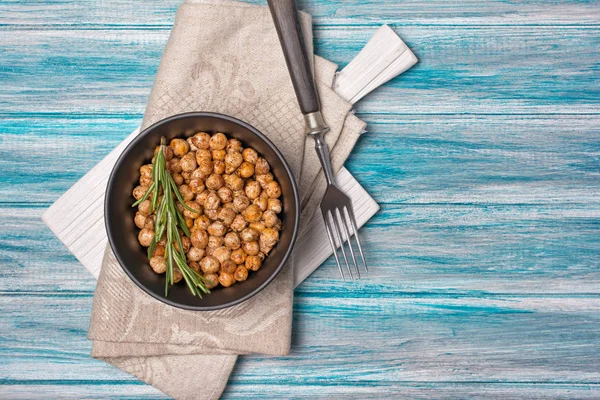 Vista dall'alto su ceci arrosto salati e piccanti in ciotola nera con rosmarino — Foto Stock