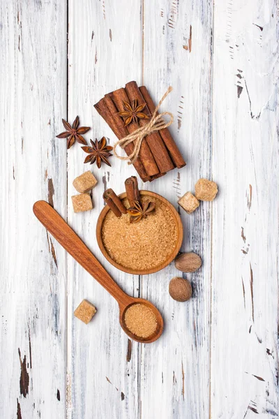 Brown cane granulated and cubes sugar in wooden bowl with spices — Stock Photo, Image