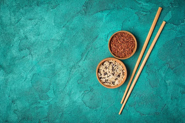 Bowls with black, white and brown or red rice with chinese chopsticks — Stock Photo, Image