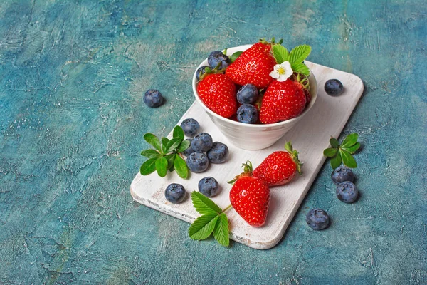 Fresas frescas y arándanos con hojas y flores —  Fotos de Stock