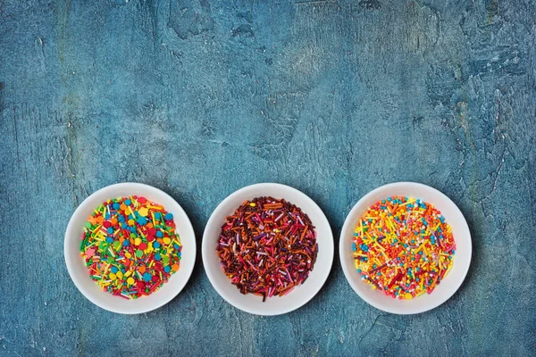 Vista superior em polvilhas de açúcar coloridas brilhantes ou confetes como decoração de cozimento — Fotografia de Stock