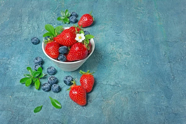 Fresas frescas y arándanos con hojas y flores — Foto de Stock