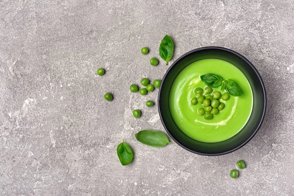 Soup of young green peas with basil leaves on gray — Stock Photo, Image