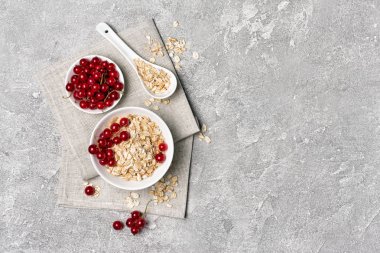 Sağlıklı kahvaltı için beyaz kase kırmızı frenk üzümü ile yulaf gevreği