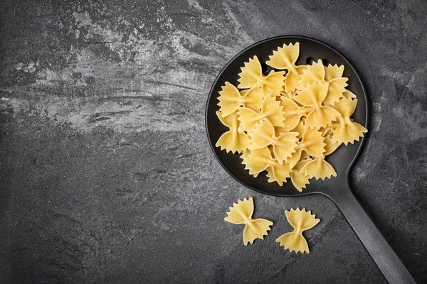 Pâtes crues farfalle en écumeur noir — Photo